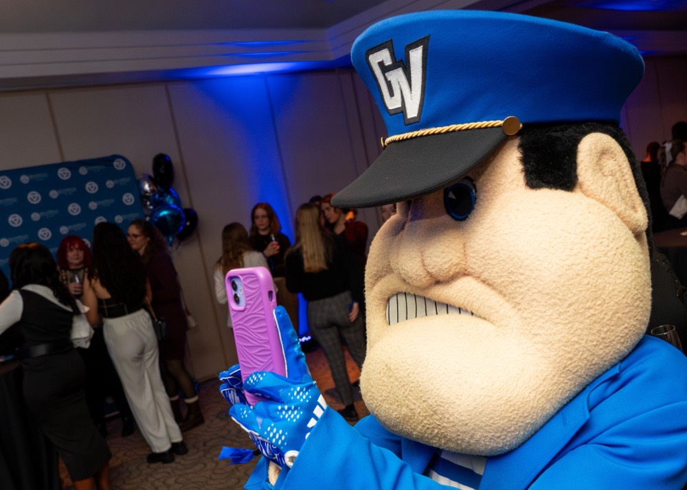 Louie the Laker takes someone's picture with a pink phone case